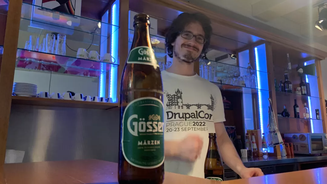 Lucas behind the bar, half hidden behind a beer bottle, clenching his left fist. 