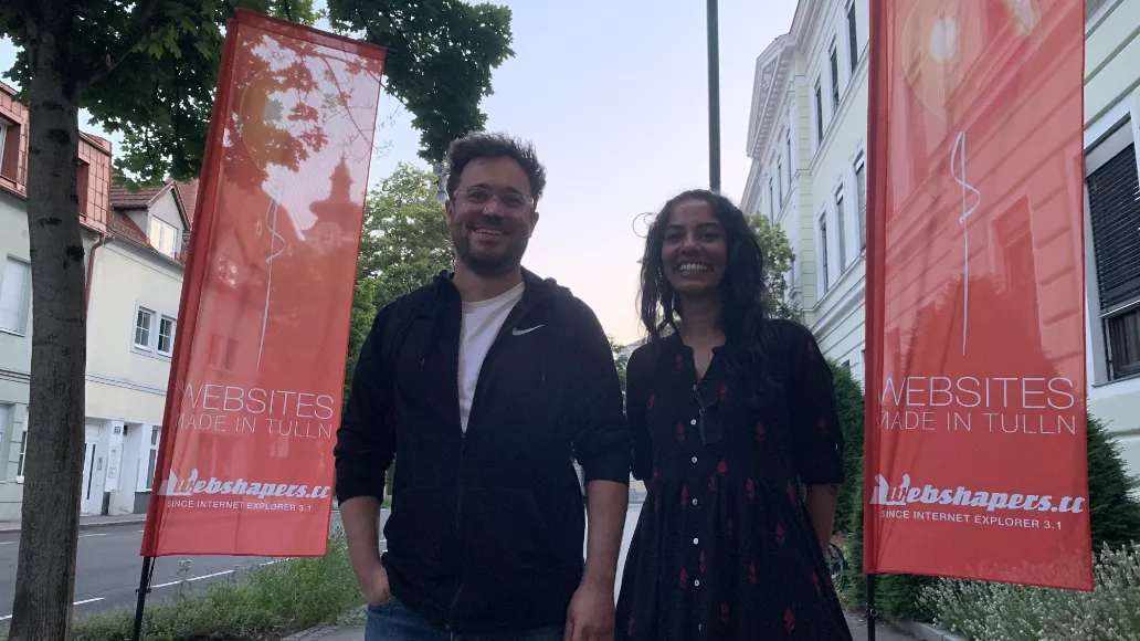 Sindhuri and Günter standing between two webshapers flags